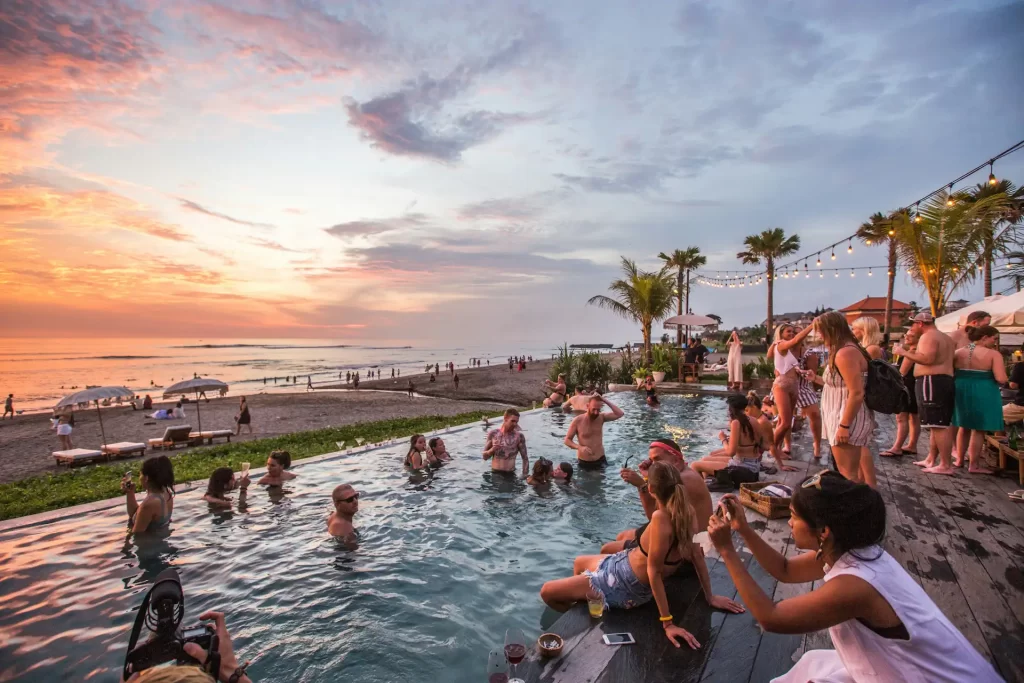 many tourist swiming in the pool watching sunsets in bali on beach view pool